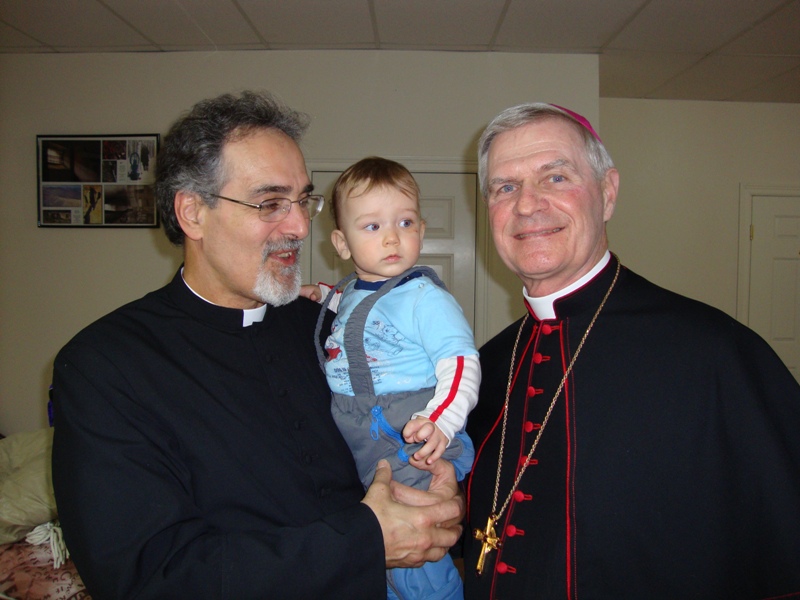Fr. Michael Holding a baby posing with another gentleman